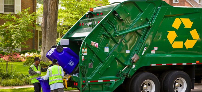 Workers empty recycling bins into a truck in a residential neighborhood in Arlington, Virginia.