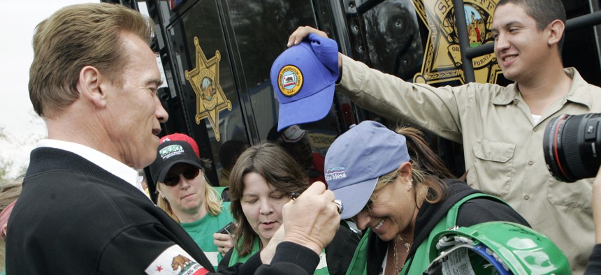 Then-California Gov. Arnold Schwarzenegger signs the cap of Cindy Brenneman, a Community Emergency Response Team (CERT) member after a news conference at the Santiago Fire Incident Command Post at Irvine Regional Park in Orange, Calif., Oct. 27, 2007.