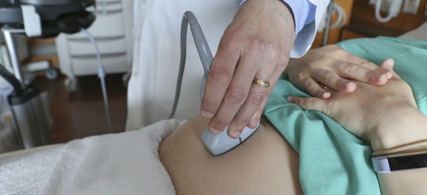 A doctor performs an ultrasound scan on a pregnant woman. Most women receive intensive medical care while they’re pregnant, but care drops off after childbirth.