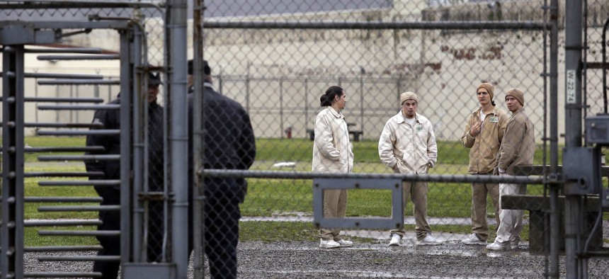In this file photo taken Jan. 28, 2016, inmates mingle in a recreation yard in view of guards, left, at the Monroe Correctional Complex in Monroe, Wash.