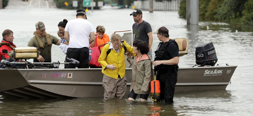 In this Aug. 27, 2017 file photo, residents are helped from a boat after being rescued from their flooded homes from Tropical Storm Harvey in Houston. 