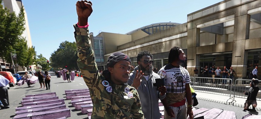 Stevante Clark, left, brother of the late Stephon Clark, raises his fist in protest while standing among mock caskets, representing black people killed by California law enforcement, during a Sept. 18 demonstration in Sacramento.