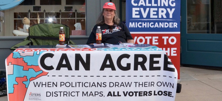 A woman on July 12, 2018 staffs a booth in Chelsea, Michigan, supporting the group Voters not Politicians at the Chelsea Sounds and Sights on Thursday Nights festival.