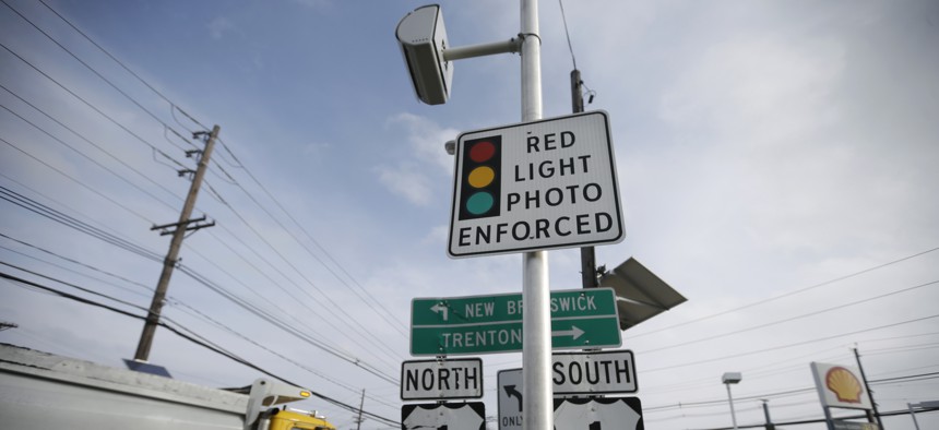 In this Dec. 16, 2014, file photo, a truck passes a red light photo enforcement sign that is placed below a red light camera at the intersection of Route 1 and Franklin Corner Road in Lawrence Township, N.J.