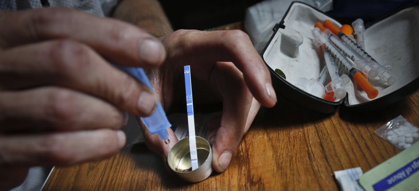 An addict prepares heroin, placing a fentanyl test strip into the mixing container to check for contamination, Wednesday Aug. 22, 2018, in New York. If the strip registers a "pinkish" to red marker then the heroin is positive for contaminants. 