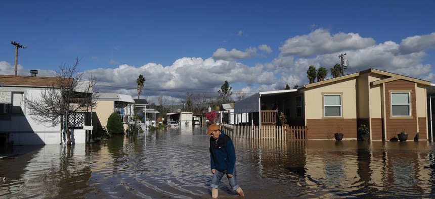 A man walks down a flooded street in South Bay Mobile Home Park in San Jose, Calif. on Feb. 22, 2017.