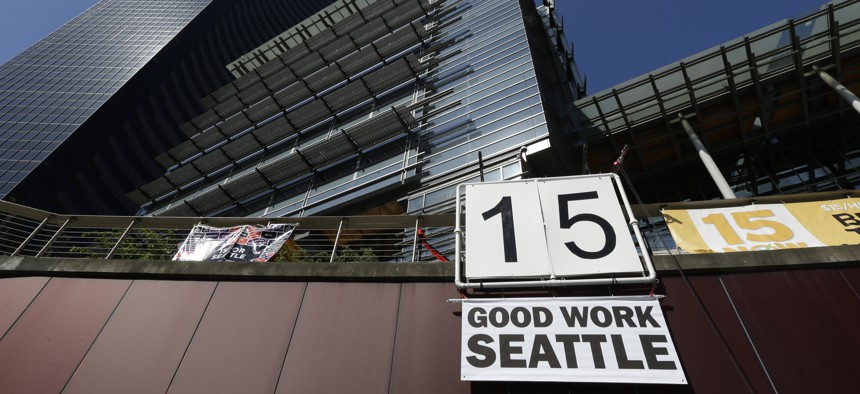 A sign that reads "15 Good Work Seattle" is displayed below Seattle City Hall, right, and the Columbia Center building, left, Monday, June 2, 2014, after the Seattle City Council passed a $15 minimum wage measure.
