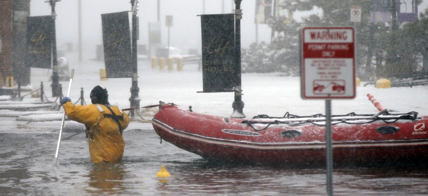 In this Jan. 4, 2018 file photo, a Boston firefighter wades through waters from Boston Harbor that flooded onto Long Wharf in Boston.