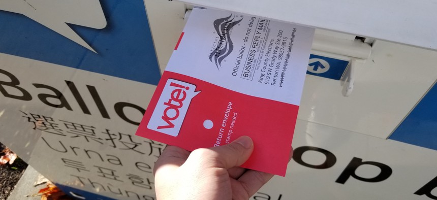 Returning a ballot at a King County Elections drop-off bin outside the Ballard branch of the Seattle Public Library.