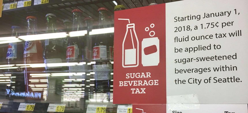 In this Sept. 24, 2018, a sign posted on a drink cooler in a store gives information about a soda tax that took effect in January, in Seattle.