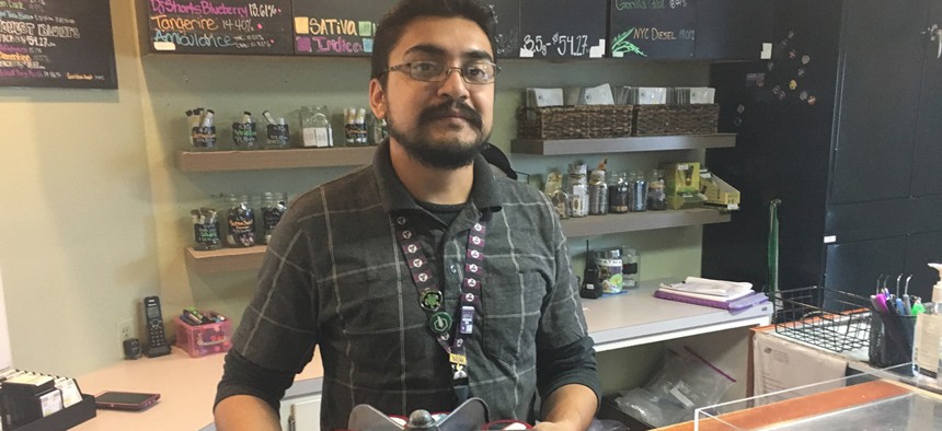 Budtender Rico Vasquez stands behind a counter displaying recreational pot products for sale at Smokey’s: A 4:20 House in Garden City, Colorado. Sales at marijuana dispensaries have created a tax revenue bonanza for the tiny town.