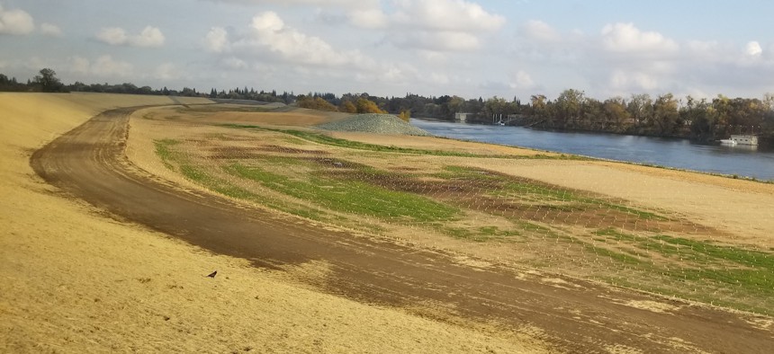A newly constructed set back levee, at left, in West Sacramento, California was constructed with gaps to allow floodwaters from the Sacramento River to flood the space between the new levee and the old one, at center..