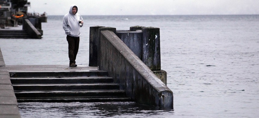 A pedestrian looks at stairs leading to water during the peak of a "king tide" Tuesday morning, Dec. 27, 2011, along Alki Beach in Seattle