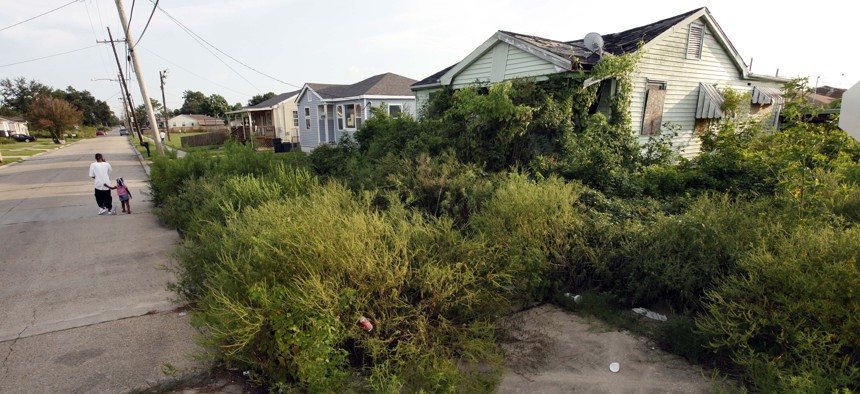 A man and child on Aug. 22, 2010 walk past a blighted home, destroyed by Hurricane Katrina and still abandoned five years after the storm, in the New Orleans East section of New Orleans.