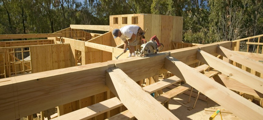 A carpenter hammers nails into the central beam while framing in southern California.