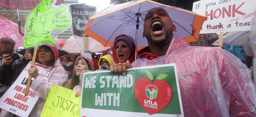 Teachers and supporters hold signs in the rain during a rally Monday, Jan. 14, 2019, in Los Angeles