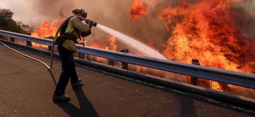 A firefighter battles a fire along the Ronald Reagan Freeway, aka state Highway 118, in Simi Valley, Calif. on Nov. 12, 2018. 