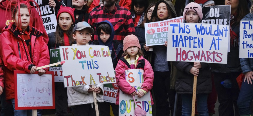Elementary students, from right, Sawyer Mack is joined by his sisters, Capri and Kaya in support of a teachers strike in front of Hamilton High School in Los Angeles on Wed. Jan. 16, 2019.