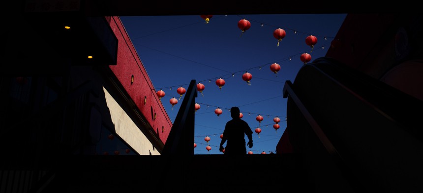 A shopper is silhouetted as he walks through a mall adorned with some Chinese lanterns in the Chinatown section of Los Angeles.