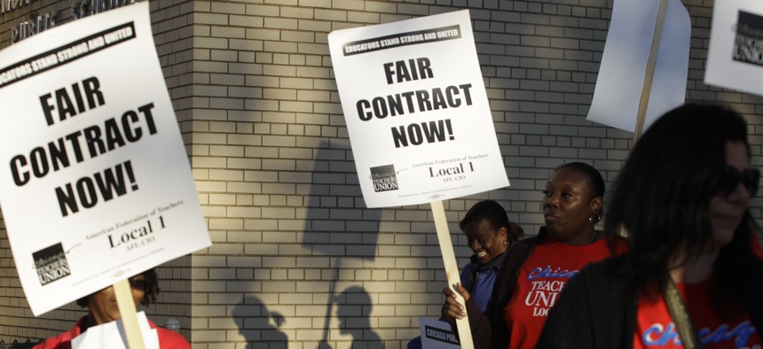 This Sept. 10, 2012 file photo shows Chicago teachers walk walking a picket line outside a school in Chicago, after they went on strike for the first time in 25 years. 