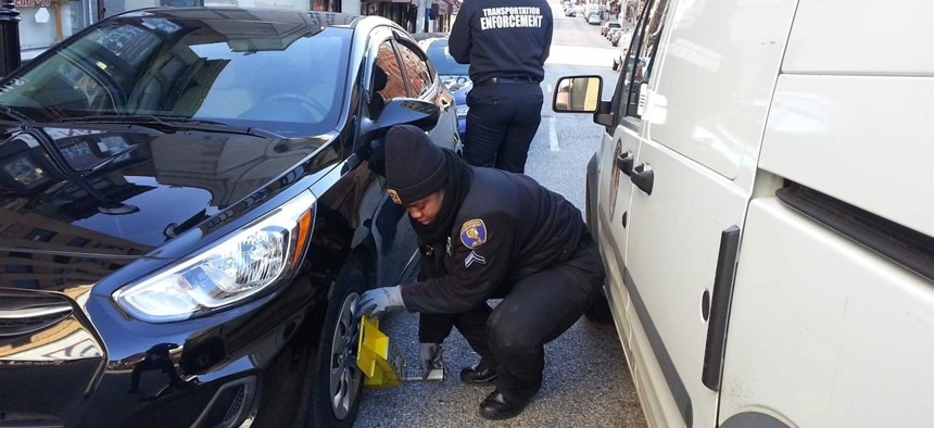 Cpl. Tiffany Chambers of the Baltimore transportation department clamps a self-release parking boot on a car on a downtown street last month. 