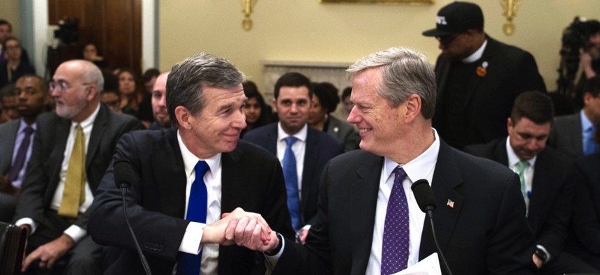 North Carolina Gov. Roy Cooper, left, and Massachusetts Gov. Charlie Baker shake hands Wednesday after testifying before the House Natural Resources Committee hearing on climate change in Washington, D.C.