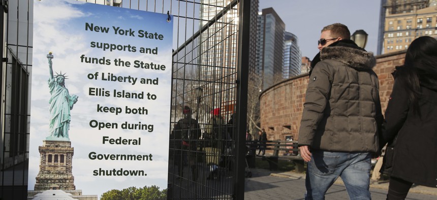 Tourists walk past a sign near the Statue of Liberty in New York, during the most recent federal government shutdown. States such as Arizona, New York and Utah have spent state money to keep national parks open during shutdowns.
