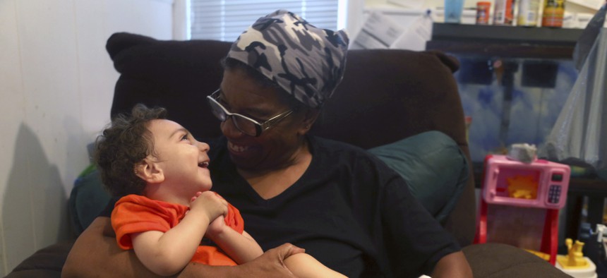 A disabled foster child smiles as he sits on his foster parent’s lap at their home in Philadelphia. More children with special needs are entering foster care, and some child welfare advocates argue foster parenting should be professionalized.