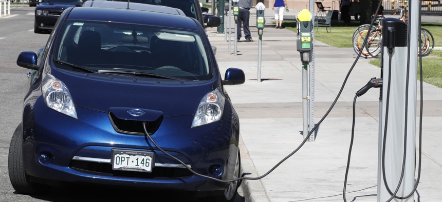 A Nissan Leaf charges at a recharge station while parked by the Denver City/County Building in downtown Denver.