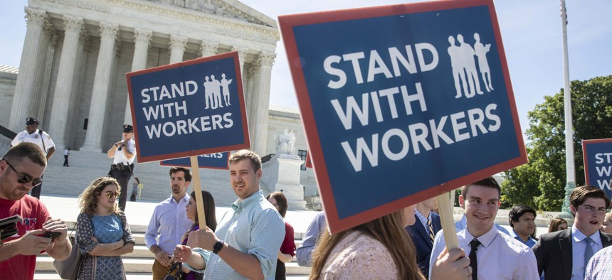 In this Monday, June 25, 2018 file photo, people gather at the Supreme Court awaiting a decision in an Illinois union dues case, Janus vs. AFSCME, in Washington.