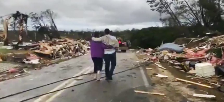 People walk amid debris in Lee County, Ala., after what appeared to be a tornado struck in the area Sunday, March 3, 2019.