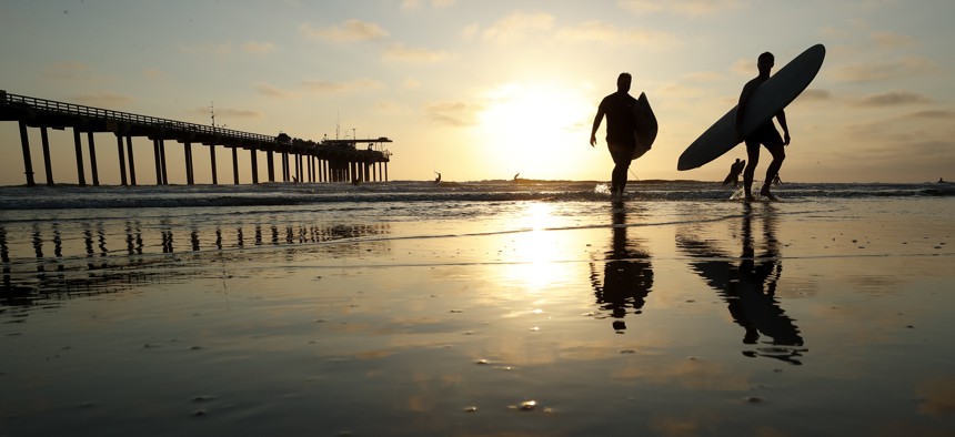 Surfers leave the water next to Scripps Pier on Aug. 2, 2018, in San Diego. The Scripps Institution of Oceanography says it has recorded the highest sea-surface temperature in San Diego in its 102 years of taking measure.