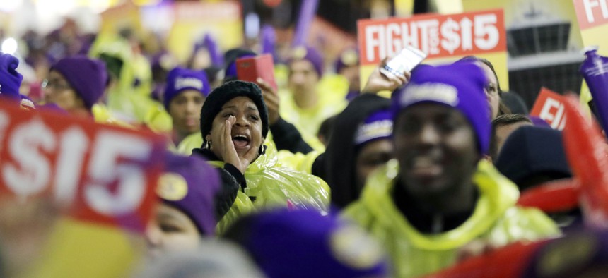 A woman shouts while marching with service workers asking for $15 minimum wage pay during a rally at Newark Liberty International Airport, Tuesday, Nov. 29, 2016, in Newark, N.J.