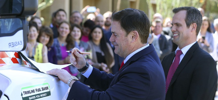 Republican Arizona Gov. Doug Ducey, left, signs into law HB 2569 making Arizona the first state in the nation to provide universal recognition for occupational licenses .
