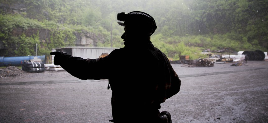 Coal miner Scott Tiller takes shelter from the rain after coming out of an underground mine at the end of a shift in Welch, W.Va. 