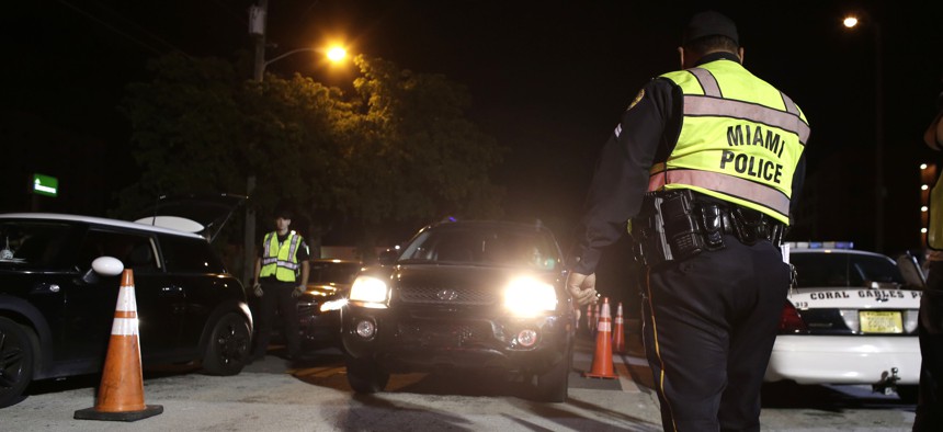 A Miami police officer guides vehicles through a 2015 drunk-driving checkpoint in Miami. 