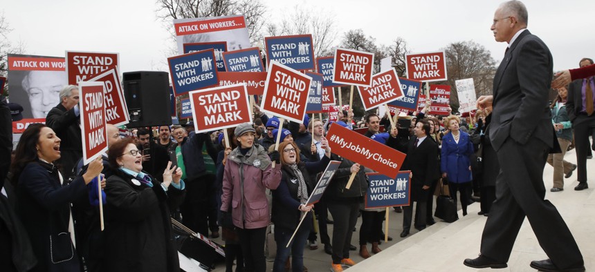 Supporters of Illinois government employee Mark Janus cheer as he walks to thank them, outside the Supreme Court, Monday, Feb. 26, 2018, in Washington. New legal disputes have arisen in the wake of the Supreme Court's decision in the case last year.