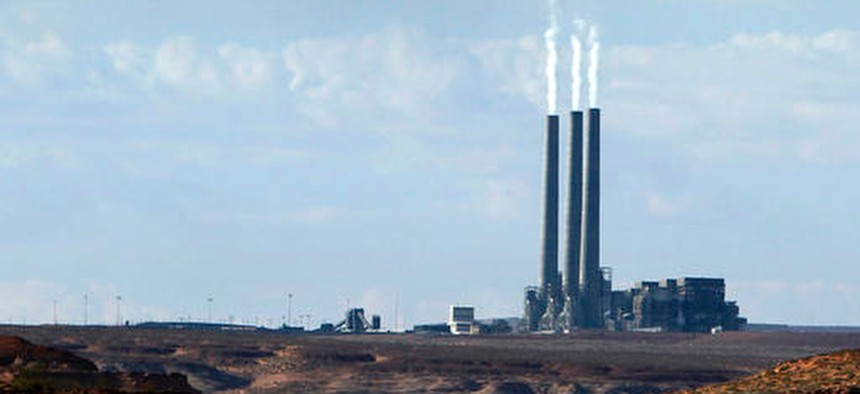 In this Sept. 4, 2011, file photo, smoke rises from the stacks of the main plant facility at the Navajo Generating Station, as seen from Lake Powell in Page, Ariz.
