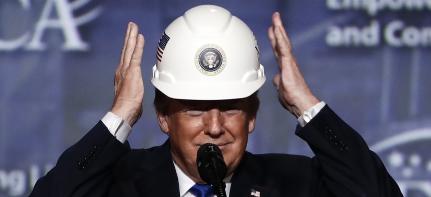 President Donald Trump puts on a hard hat given to him before he speaks at the National Electrical Contractors Association convention in Philadelphia on Oct. 2, 2018.