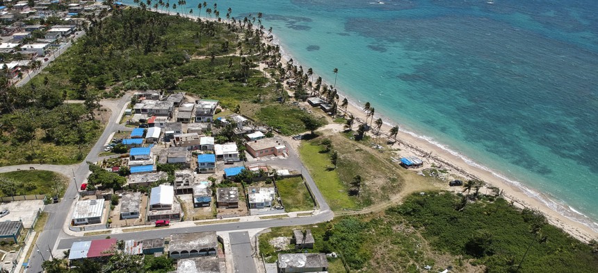 This June 2018 photo shows an aerial view of the Viequez neighborhood, east of San Juan, Puerto Rico.  Nine months after Hurricane Maria, blue plastic tarps still protected thousands of homes.