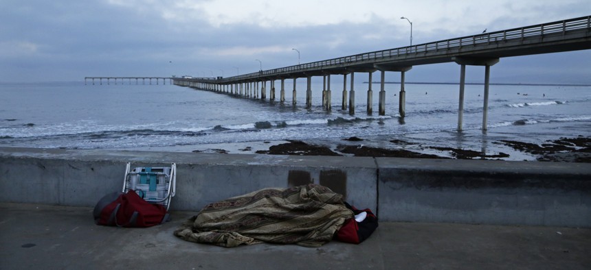 A homeless person sleeps on a beach near the Ocean Beach Pier in San Diego.