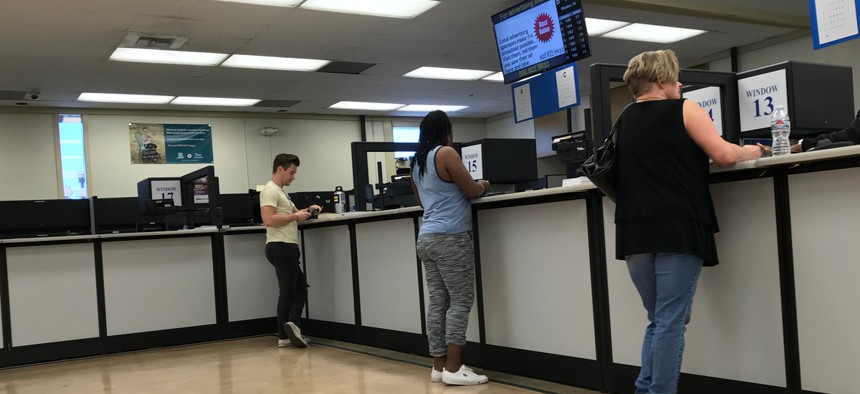 People standing at the counter inside the DMV field office in Culver City, California.