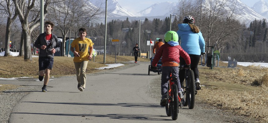 This April 3, 2019, photo shows people running and biking at Westchester Lagoon in Anchorage, Alaska, with the snow-covered Chugach Mountains in the distance. Much of Anchorage's snow disappeared as Alaska experienced unseasonably warm weather in March.