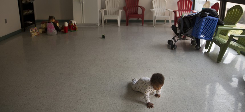 A baby crawls toward her mother at a homeless shelter in Los Angeles.