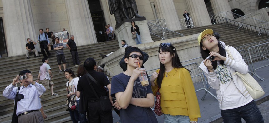 A group of tourists from China take in the sights of the New York Stock Exchange and Federal Hall National Memorial, in New York. 
