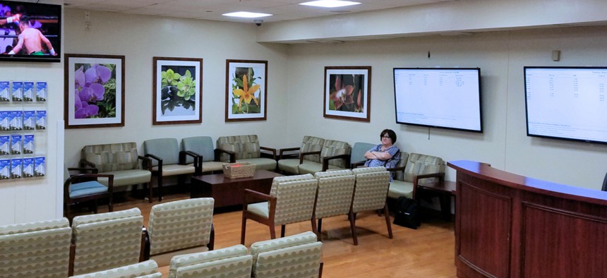 A lone woman sits in a hospital waiting room.