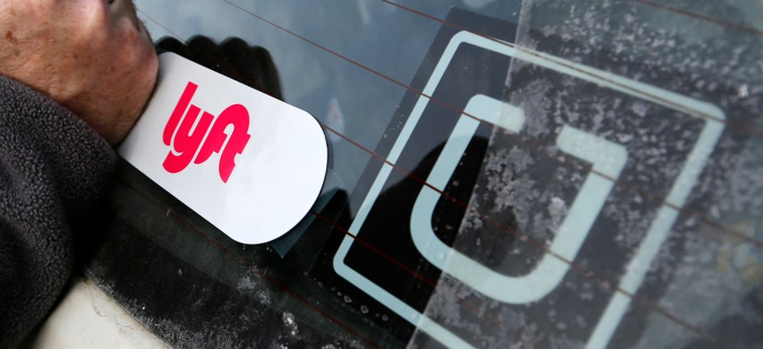 In this Jan. 31, 2018, file photo, a Lyft logo is installed on a Lyft driver's car next to an Uber sticker in Pittsburgh. 