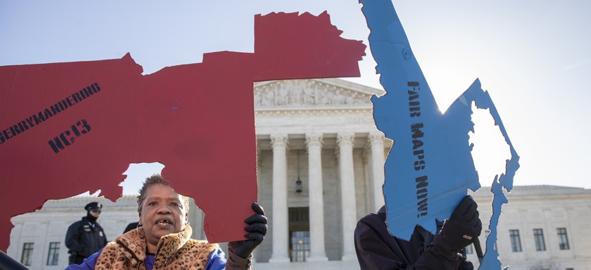 Activists at the Supreme Court opposed to partisan gerrymandering hold up representations of congressional districts from North Carolina, left, and Maryland, right.