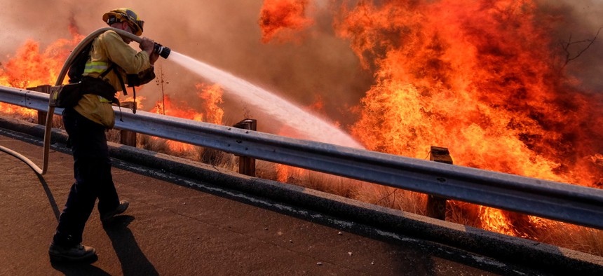 In this Nov. 12, 2018 file photo a firefighter battles a fire along the Ronald Reagan Freeway, aka state Highway 118, in Simi Valley, Calif. 