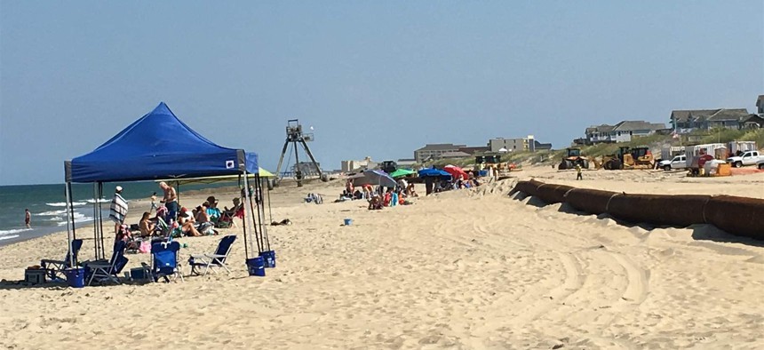 Pipes for a beach renourishment project lie along the coastline among tourists’ umbrellas and canopies in Nags Head, North Carolina. The project, expected to be complete by September, will pump 4 million cubic yards of sand onto a 10-mile stretch of beach